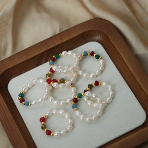 Handmade natural pearl and gemstone rings set on a wooden tray with champagne silk cloth