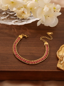 Detail of 18K gold snake chain bracelet with pink crystals and adjustable clasp on wood
