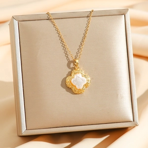 Elegant gold clover pendant necklace with white mother of pearl on satin background