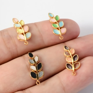 Mini colorful enamel leaf pendants on fingers showing small size for DIY jewelry