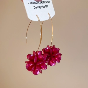 Dettaglio di orecchini lunghi con pendenti a fiore magenta e ganci dorati