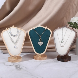 Three premium velvet necklace busts in wood and green finishes on marble tabletop