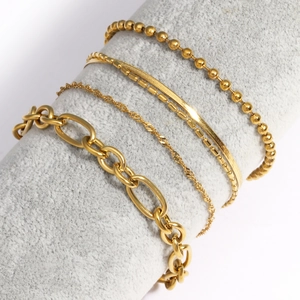 Détail de cinq chaînes diverses en acier inoxydable doré sur un support à bijoux gris