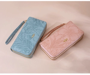 Detail of floral embossed texture on dual zipper long wallet with wristlet strap