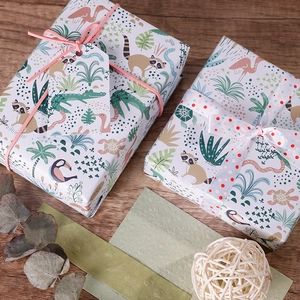 Jungle animal print gift wrapping paper on two gift boxes with pink ribbons on wood surface