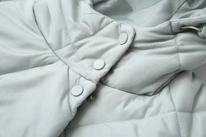 Close-up of light blue quilted jacket featuring diamond stitching and matching buttons