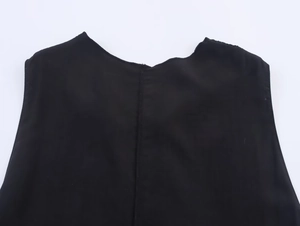 Detailaufnahme des schwarzen Neckholder-Tops mit glatter Textur und Brosche-Element