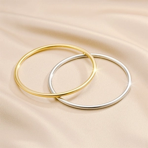 Detailansicht minimalistischer Armreifen aus Titanstahl in Gold und Silber auf Seide