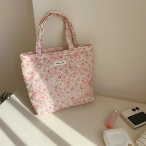 Close-up of pink floral quilted tote bag featuring a simple wish label on a white surface