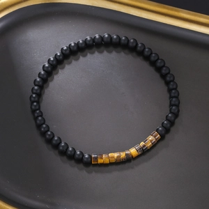 Minimalist beaded bracelet featuring matte black beads and tiger eye stones on a tray