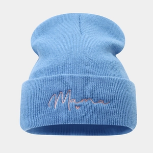 Detailopname van blauwe gebreide muts met roze Mama-borduring en hartjespatroon