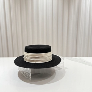 Detail of black boater hat featuring pearl-embellished cream ribbon and fine woven texture
