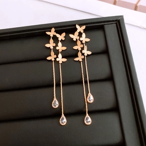 Detail of 18K gold-plated butterfly tassel earrings with drop-shaped crystals on black tray