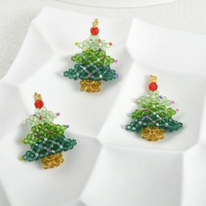 Detailed view of three handmade green crystal beaded Christmas tree charms on a plate