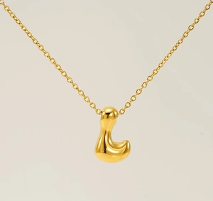 Macro view of gold bubble letter L pendant with a polished mirror finish on cross chain