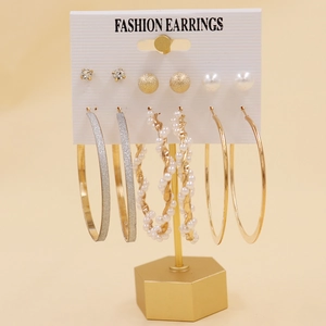 Détail d'un ensemble de six boucles d'oreilles dorées avec perles et strass sur carte