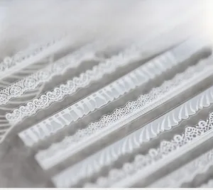 Détail macro de stickers ongles dentelle blanche avec motifs floraux et ondulés fins