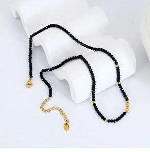 Macro detail of black beaded necklace with gold accents and adjustable lobster clasp closure