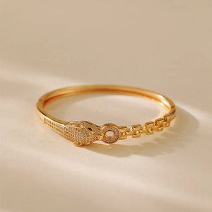 Macro shot of gold-plated leopard head bracelet with white zircons and green gemstone eyes