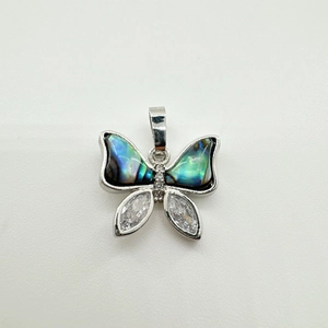 Vue macro du pendentif papillon avec ailes en nacre dorée 18K et détails en zircon