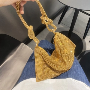 Detailed close-up of golden rhinestone handbag with unique knotted handle design