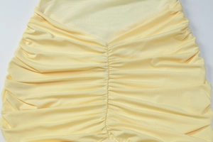 Detail of the pale yellow fabric featuring intricate ruched texture and gathered design