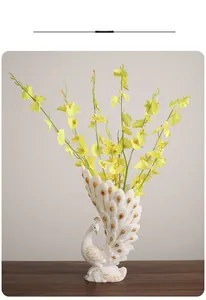 Close-up of white peacock vase with gold trim and yellow dancing orchid flowers