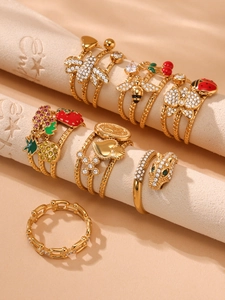 Macro detail of gold-plated rings with zircon ladybug, strawberry, and snake charms