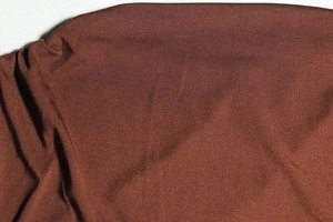 Detailed close-up of brown textured fabric with fine knit structure and stitched seams