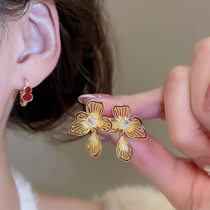 Detailed close-up of gold-plated flower earrings with pear-cut zircon and teardrop charms