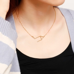 Golden constellation pendant necklace with sparkling stone accents on female model neck