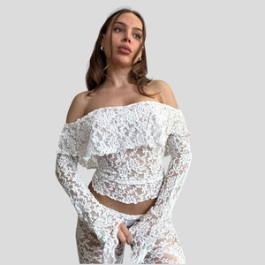 Detail of white hollow lace pattern on the sexy off-shoulder top and flared trousers set