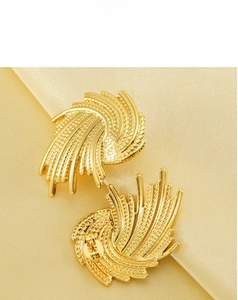 Detailed view of golden swirling fan-shaped stud earrings on luxury silk background
