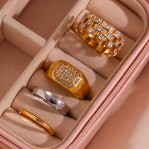 Detail of four gold and silver rings with cubic zirconia in a pink suede jewelry box