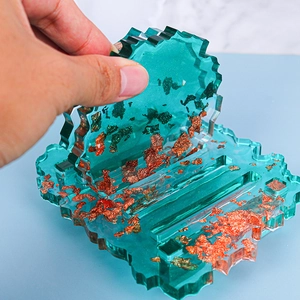 Detail of green translucent resin coaster with gold foil being inserted into base