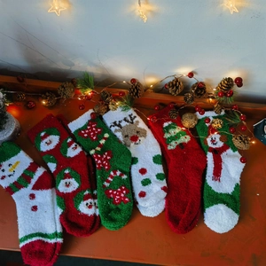 Close-up of festive coral fleece Christmas socks featuring reindeer and snowmen patterns