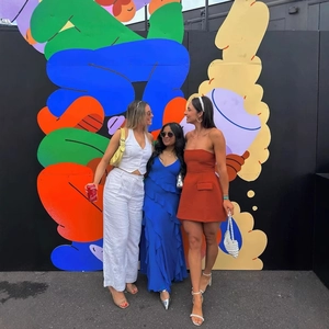 Elegante abito corto a fascia e set di moda mostrati davanti a una parete d'arte colorata