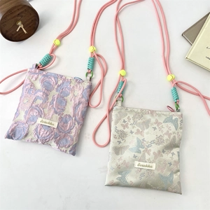 Detail view of jacquard floral and butterfly print phone bags with adjustable rope straps
