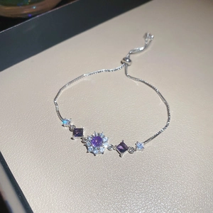 Close-up of adjustable silver bracelet featuring purple gemstones and sparkling zircon flowers