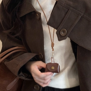 Close-up of a dark brown mini leather bag pendant with a vintage metal snap button