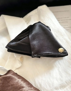 Détail de la pince à cheveux en satin noir avec boucle en métal doré sur chemise