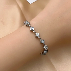 Detailed view of silver cube bracelet with sparkling cubic zirconia on champagne silk
