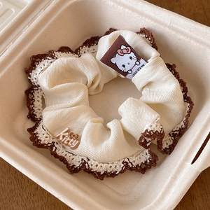 Detailed view of cream plaid scrunchie with lace edge and cute character accent