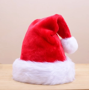 Classic plush red and white Christmas hat displayed on a light wooden table surface
