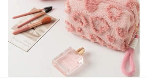 Close-up of pink faux fur toiletry bag with heart patterns and soft rope handle