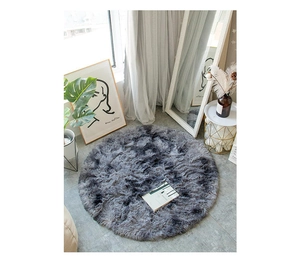 Close-up of soft dark gray shaggy round rug texture on minimalist wooden floor