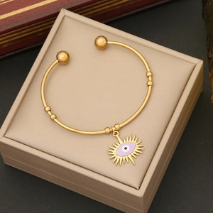 Detail of gold evil eye bracelet with purple enamel pendant in a jewelry gift box