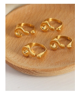 Detailed view of four golden question mark shaped rings on a round wooden tray