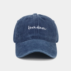 Close-up of white baba embroidery on washed navy denim fabric of the baseball cap