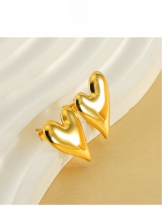Close-up of heart-shaped 18K gold-plated titanium earrings on a wavy stand